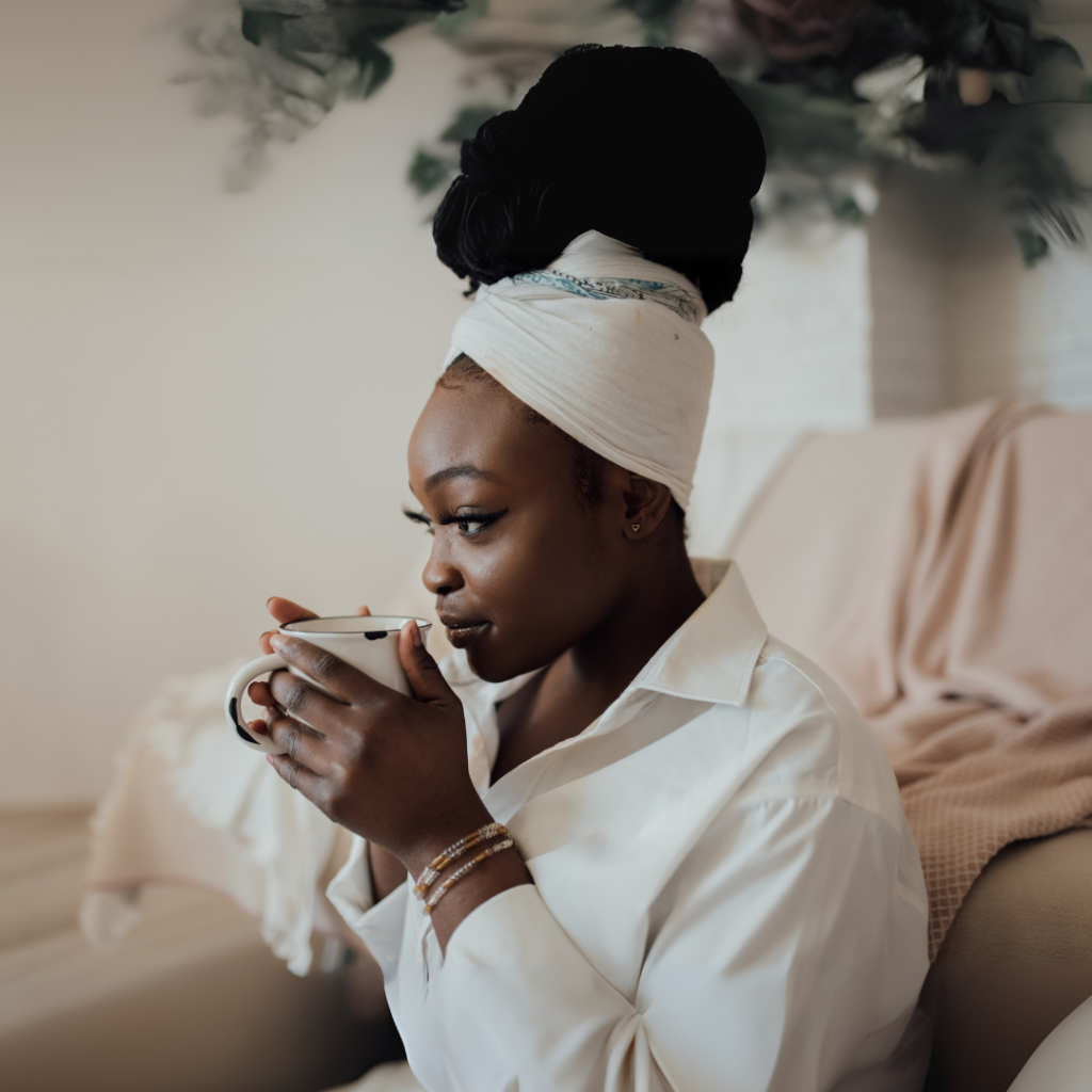 Woman relaxing in her home sipping coffee as part of her summer reset ritual. Omni Coffee Studio recommends pausing for still moments as part of self-care.